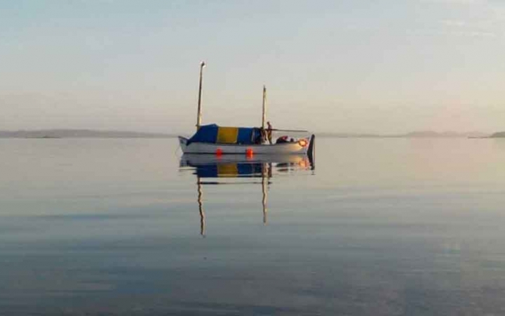 a sailboat rests in still water on an outward bound expedition in maine